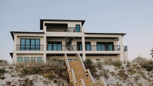 Un edificio frente al mar de varios pisos, con una escalera que lleva a la entrada.