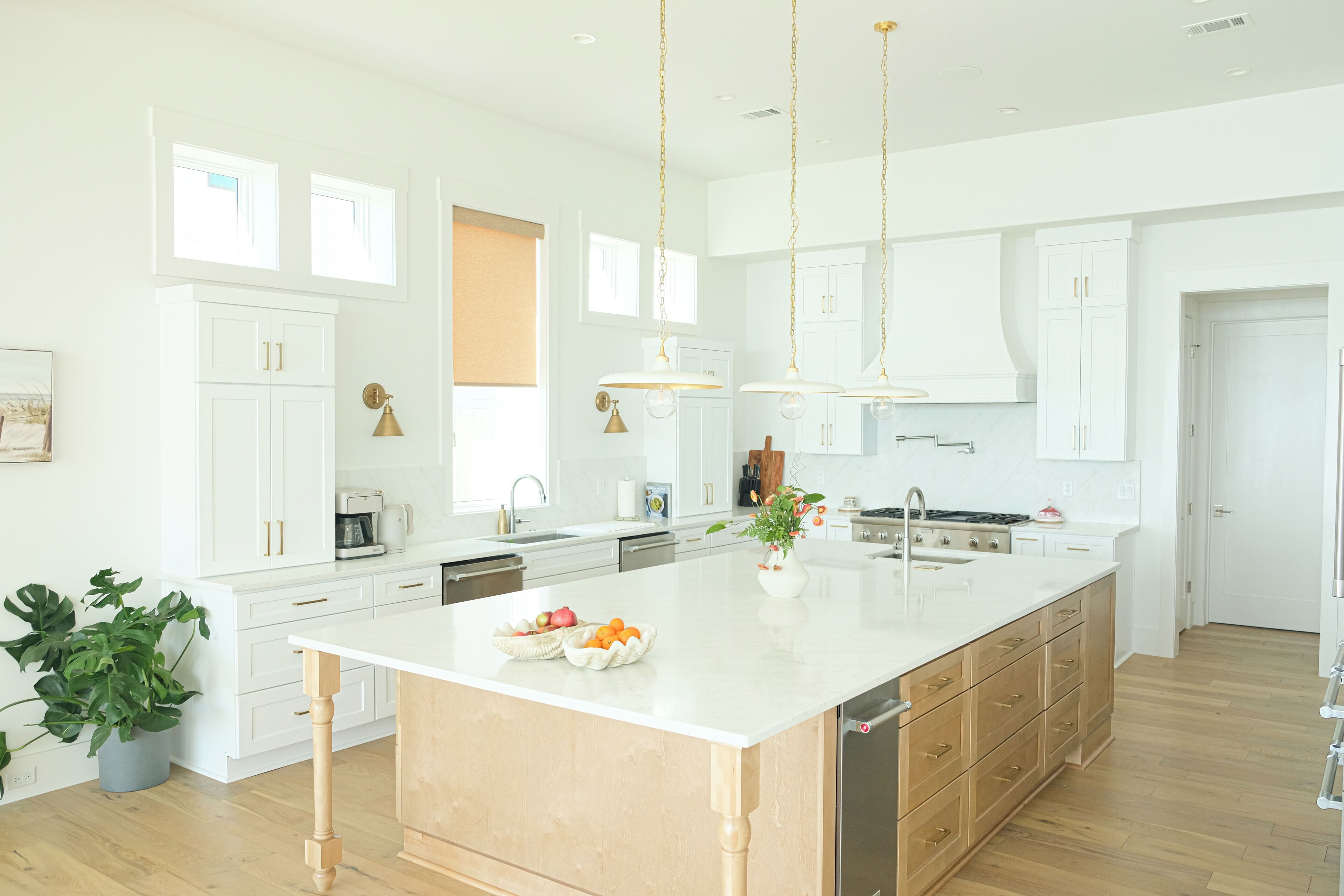 Una cocina moderna con armarios blancos, una isla grande e iluminación colgante.