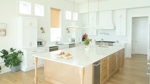Una cocina moderna con armarios blancos, una isla grande e iluminación colgante.