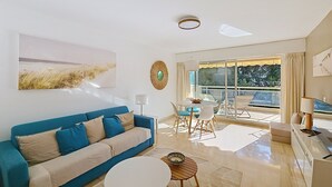 A modern living room with a blue sofa, a round coffee table, and a dining area with a table and chairs. - HENRI CAMILLE RE - Passy1 -Beautiful one bedroom swimming pool and parking (Cannes)