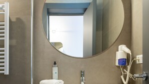 A bathroom with a round mirror, white sink, towel rack, and a hairdryer. - Hotiday Torre Lapillo Centro (Torre Lapillo)