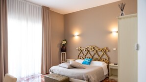 A bedroom with a bed, bedside tables, a nightstand, a vase with flowers, and a lamp. - Hotiday Porto Cesareo Spiaggia (Porto Cesareo)