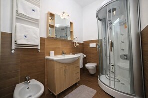 A modern bathroom with a glass-enclosed shower, a sink, a bidet, and a toilet. - Hotiday Porto Cesareo Spiaggia (Porto Cesareo)