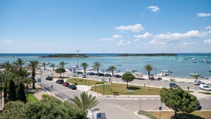 A coastal road with parked cars, a parking sign, and boats in the water. - Hotiday Porto Cesareo Spiaggia (Porto Cesareo)