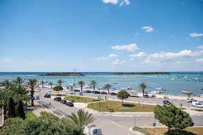 A coastal road with parked cars, a parking sign, and boats in the water. - Hotiday Porto Cesareo Spiaggia (Porto Cesareo)