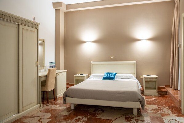 Une chambre d’hôtel avec un lit, des tables de chevet, un bureau et une chaise.