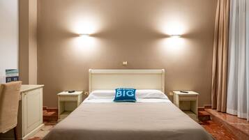 A hotel room with a bed, two bedside tables, a desk, a chair, and a curtain.