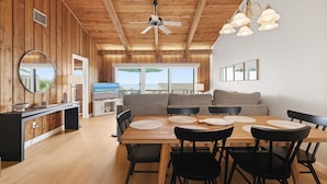 A wooden interior with a dining area, a ceiling fan, and a television. - Sea Dunes Nautilus B7-a (New Smyrna Beach)