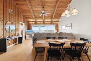 A wooden interior with a dining area, a ceiling fan, and a television. - Sea Dunes Nautilus B7-a (New Smyrna Beach)