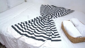 A bed with a white comforter, a black and white striped blanket, and a woven basket with a white towel. - Studio M - Tiny house kesbah de tanger (Tanger)