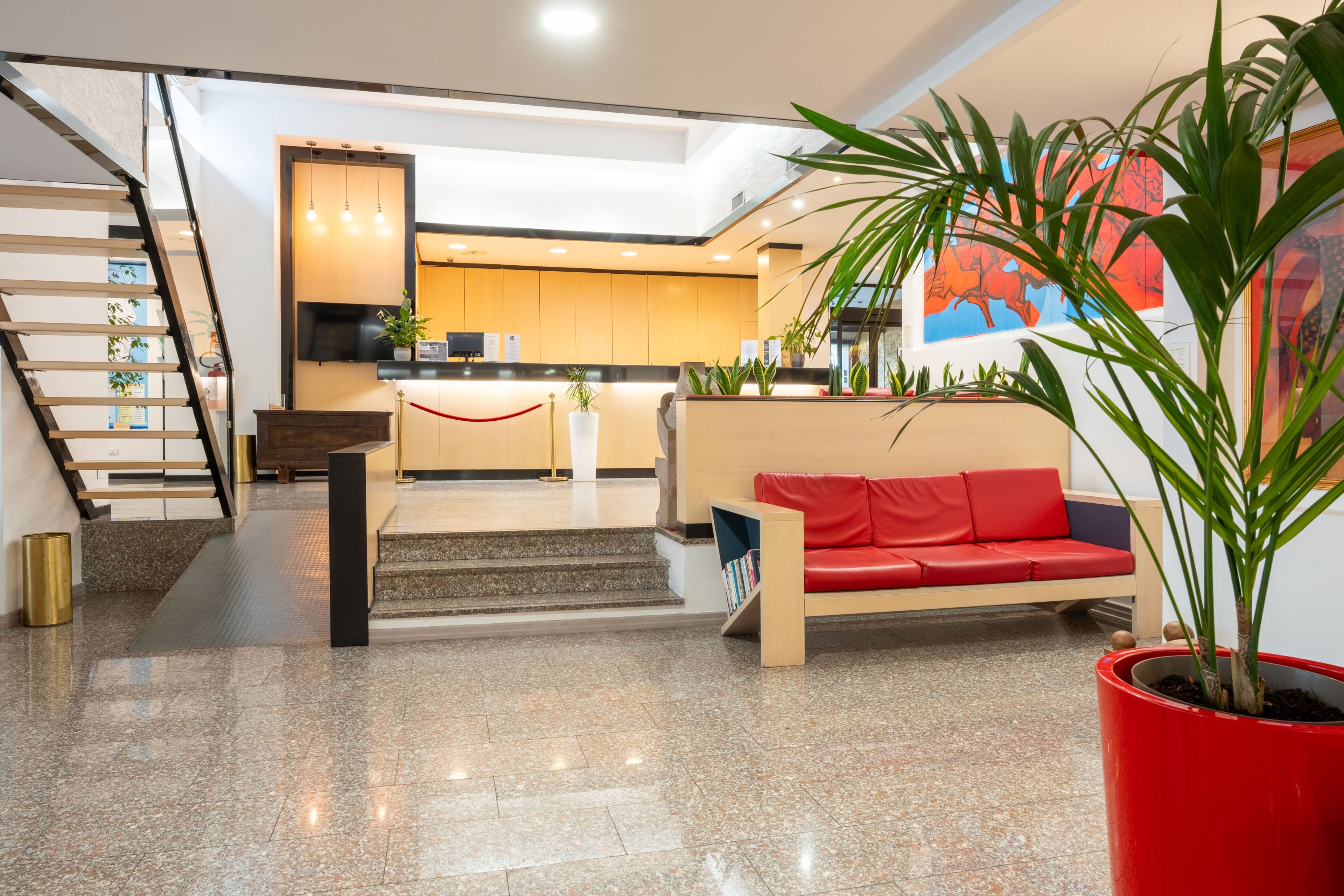 Un intérieur moderne avec un escalier, un canapé rouge et un coin cuisine.
