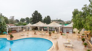 A swimming pool with lounge chairs and umbrellas, surrounded by potted plants and covered areas. - Hotiday Cagliari Sant'Elena (Quartu Sant'Elena)