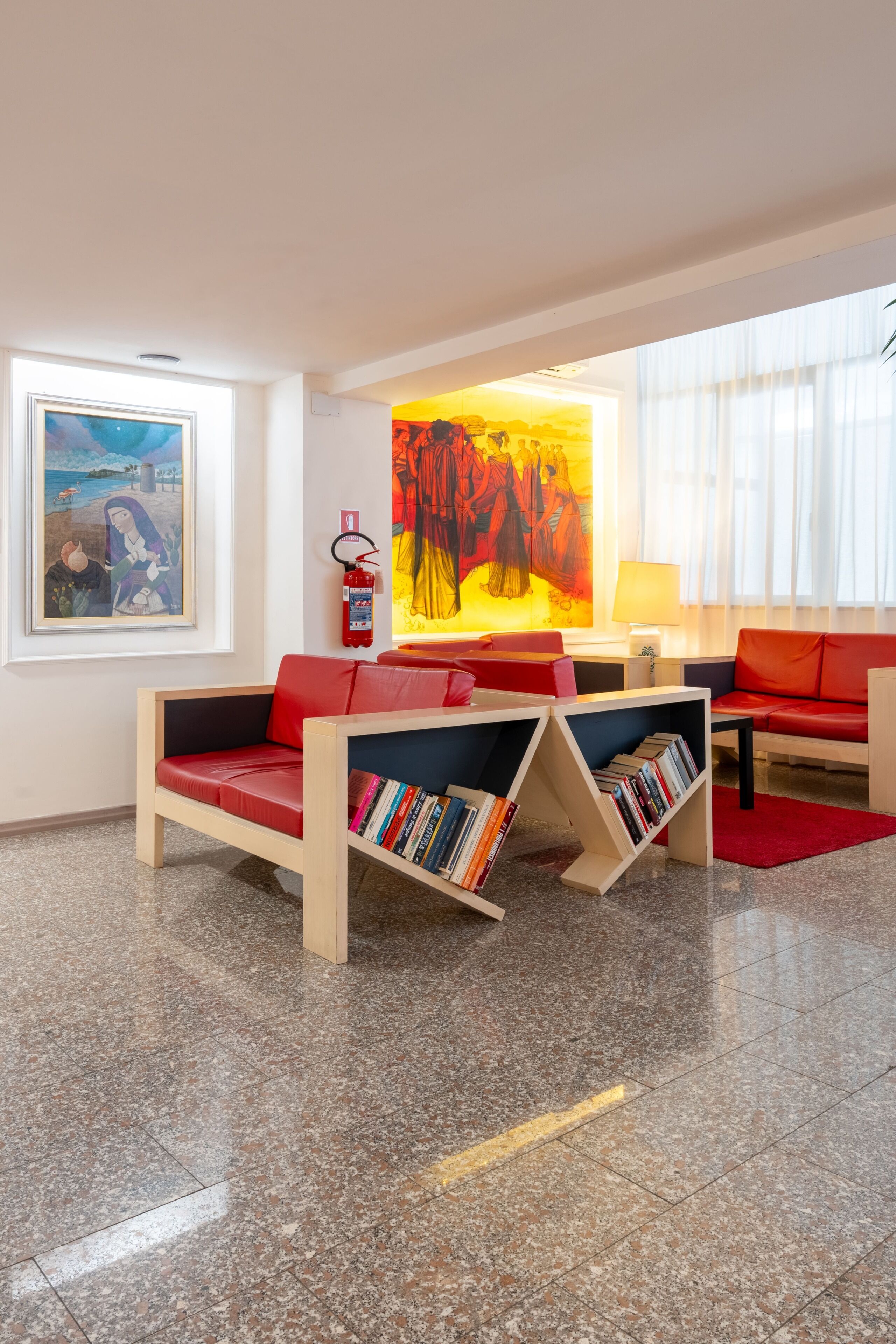 Una sala de estar moderna con un sofá rojo, una estantería, un cuadro y un extintor.