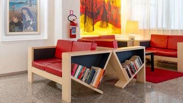 Una sala de estar moderna con un sofá rojo, una estantería, un cuadro y un extintor.