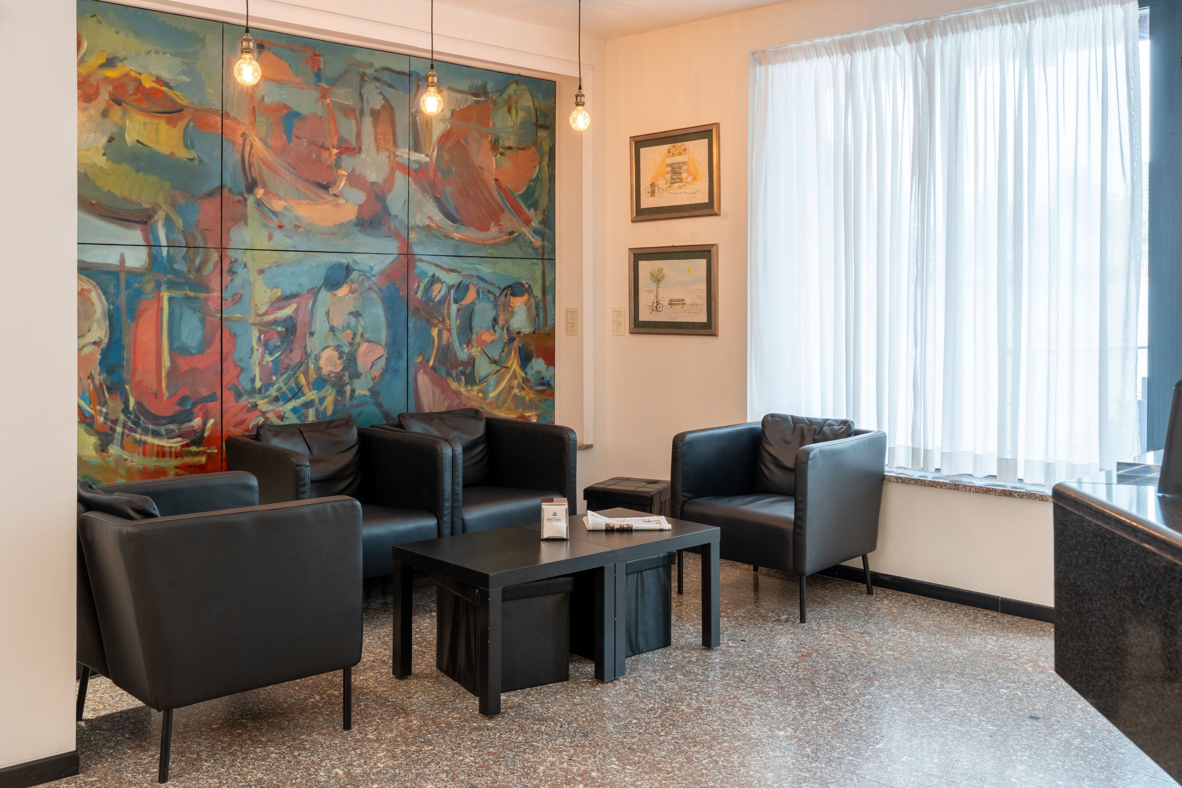 Un vestíbulo moderno con arte abstracto, asientos de cuero, una mesa de centro y un amplio ventanal con cortinas.