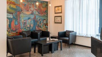 Un vestíbulo moderno con arte abstracto, asientos de cuero, una mesa de centro y un amplio ventanal con cortinas.
