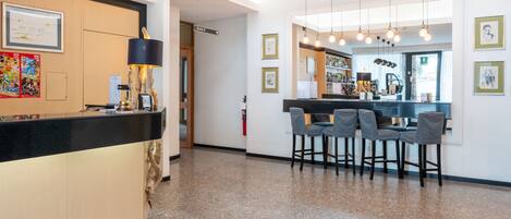 A modern hotel lobby with a reception desk, bar area, and seating.
