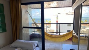 Una camera d'hotel con un letto, un tavolino e vista sulla spiaggia tramite una porta vetrata.