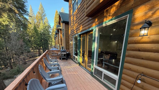 A wooden deck with outdoor seating and a view of the forest.