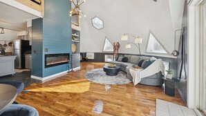 Ein modernes Wohnzimmer mit Kamin, einer Couch und einem Essbereich.