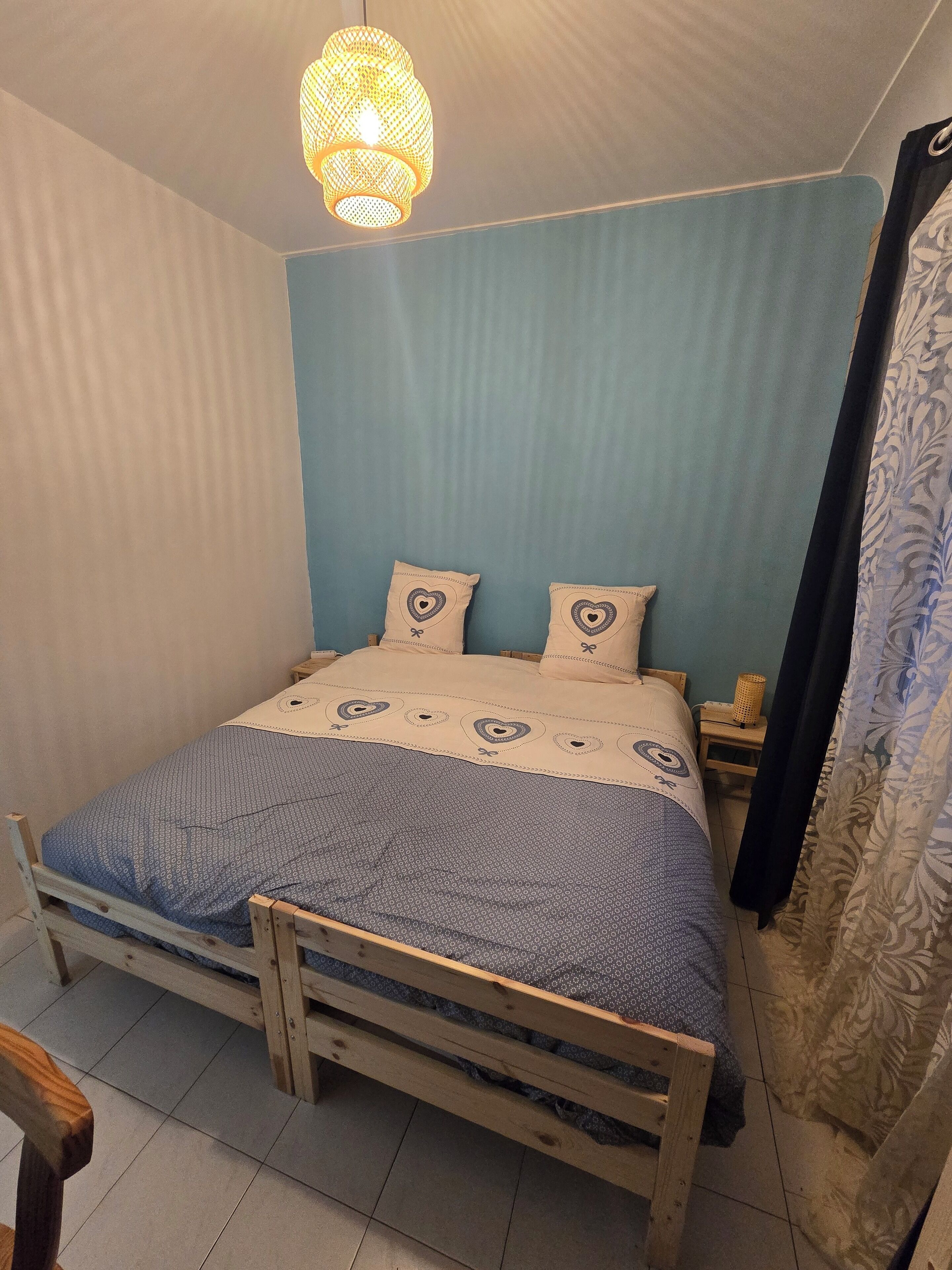 A bedroom with a wooden bed, a blue wall, and a hanging light fixture.