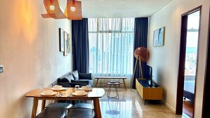 A modern living room with a dining area, large windows, and a view of the cityscape. - Vortex Suites Klcc By Bukit Bintang (Kuala Lumpur)