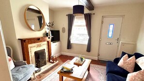 Una sala de estar con chimenea, un sofá, una mesa de centro y un tapete estampado.
