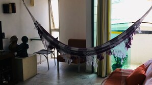 Ein Wohnzimmer mit einer Hängematte, einem Sofa, einem Couchtisch und Blick ins Freie.