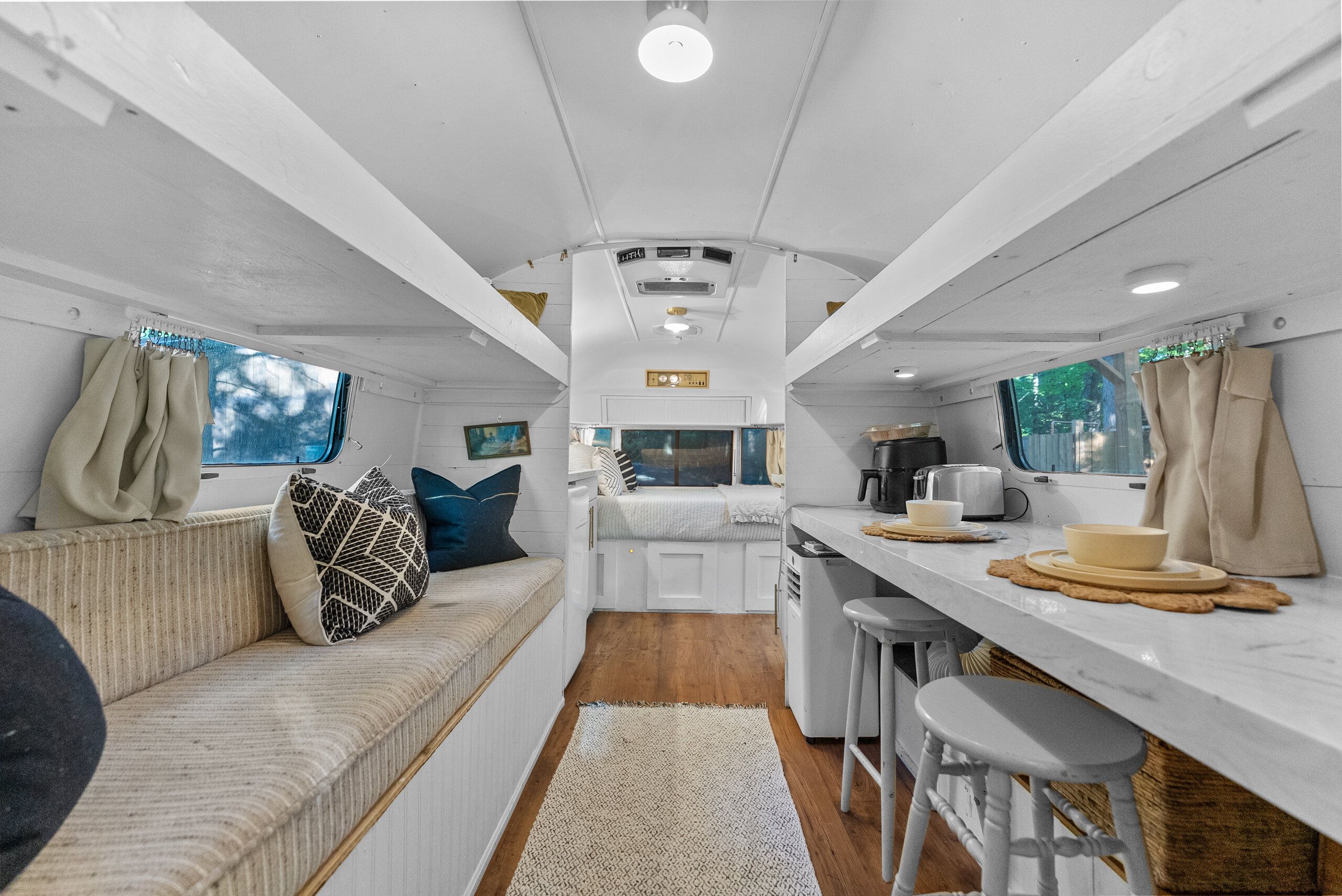 Interior compacto de una caravana con kitchenette, zona de estar y ventana.
