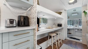 Una cocina moderna con armarios blancos, una cafetera y taburetes de bar.