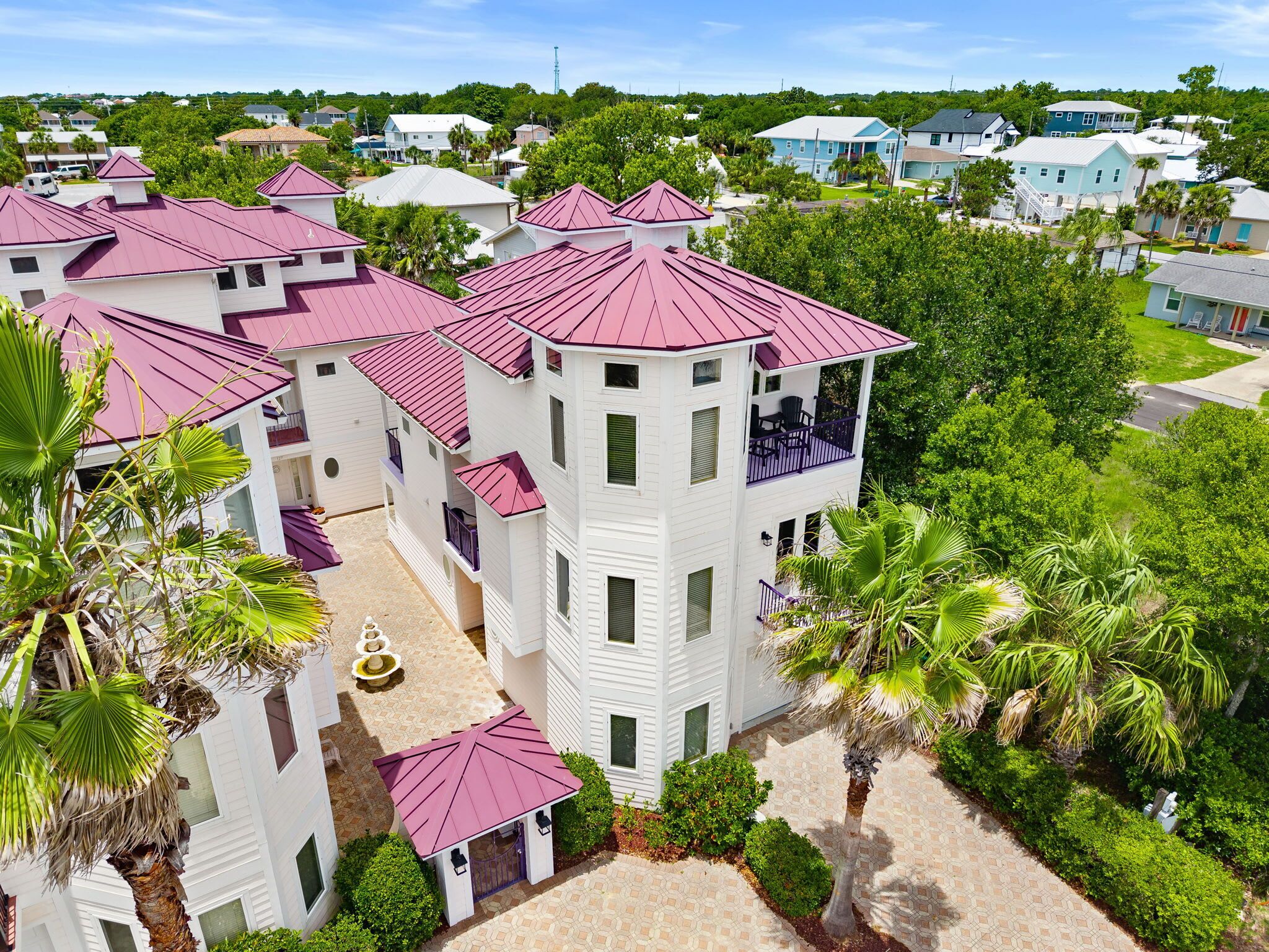 A multi-story building with a central courtyard, surrounded by lush greenery and palm trees.