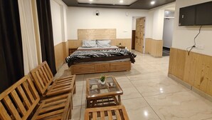 A bedroom with a bed, wooden furniture, a TV, and a ceiling light. - Hils & Paw (Manali)