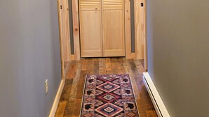 Un pasillo con puertas de madera, un tapete estampado y un suelo de tono claro.
