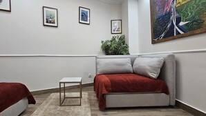 A hotel room with a bed, a small table, a sofa, and a large painting on the wall.