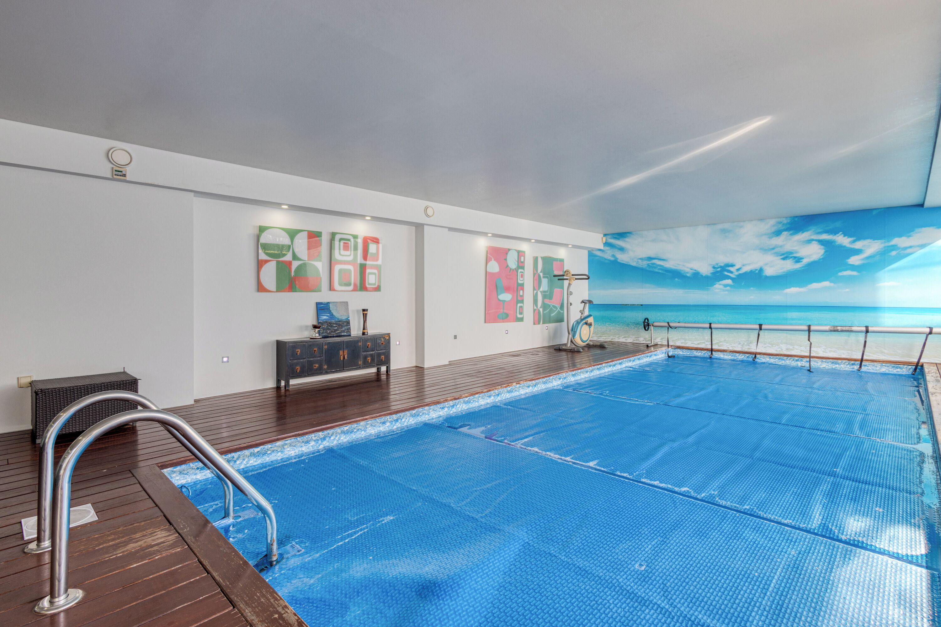 Een binnenzwembad, parasols bij het zwembad en ligstoelen