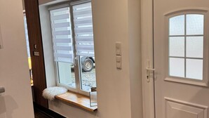 Un pasillo con una puerta, un ventanal con una banca y vistas al exterior.
