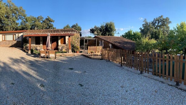 A rustic building with a tiled roof, a gravel driveway, and a wooden fence.