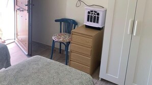 A room with a bed, a desk, a chair, a wardrobe, and a TV mounted on the wall.