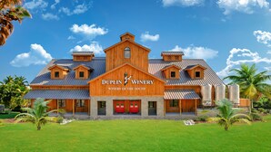 Een groot houten gebouw met een bord waarop staat: "DUPLIN WINERY WINERY OF THE SOUTH".