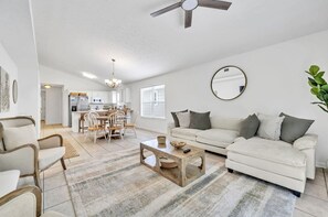 Ein stilvolles Wohnzimmer mit einem weißen Sofa, einem Couchtisch und einem Essbereich mit Holzkästen.