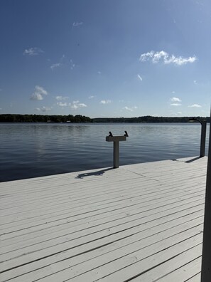 A wooden dock extending over calm water with a clear sky.