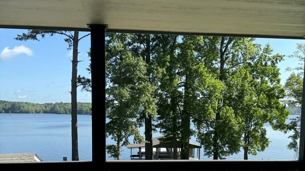 A wooden deck with a view of a lake and trees.