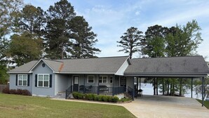 A two-story house with a covered porch, a front lawn, and a view of a lake.