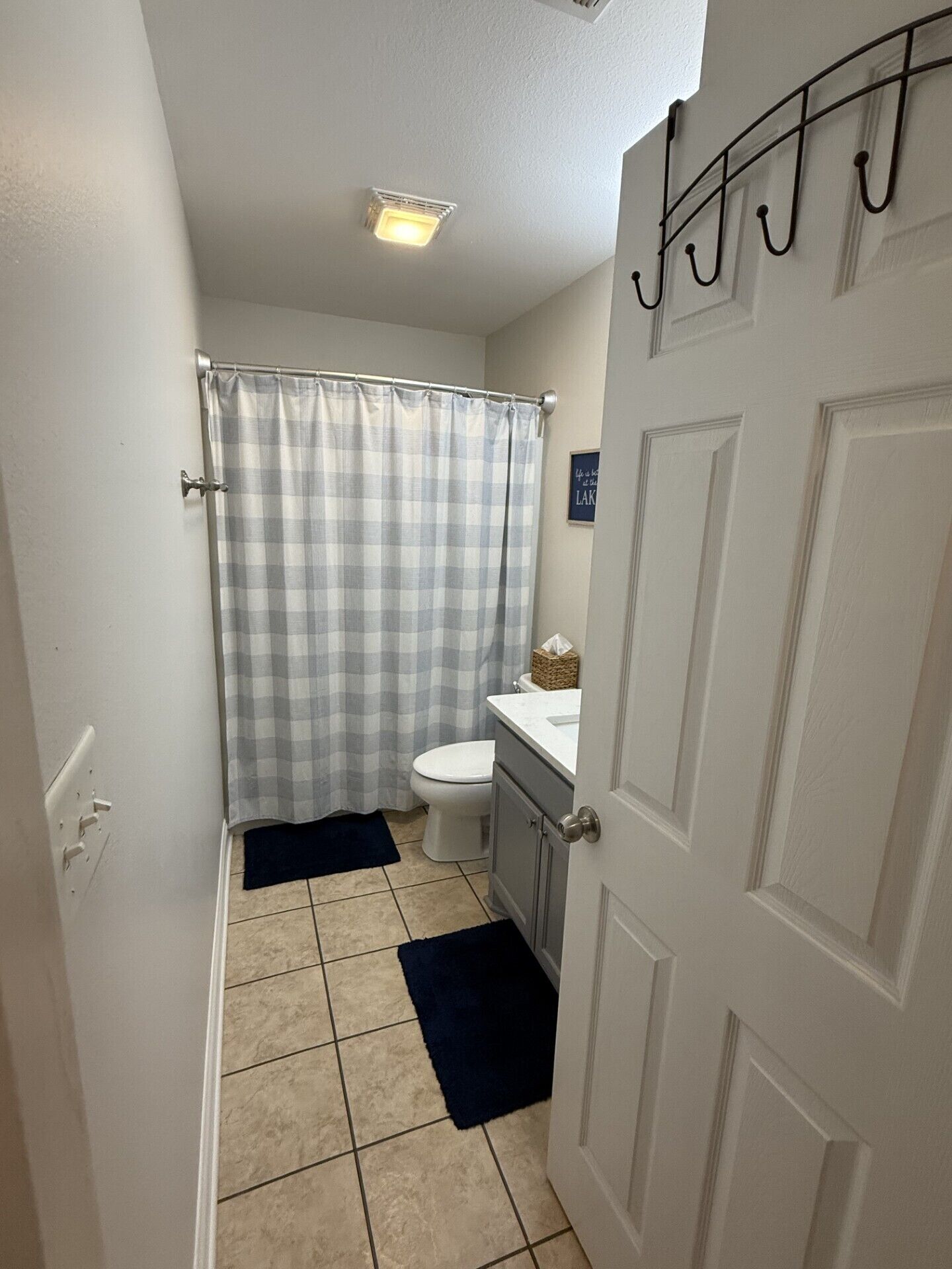 Ein Badezimmer mit Toilette, Waschbecken, Duschvorhang und Handtuchhalter.