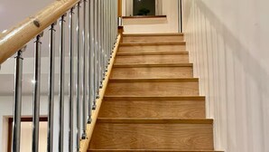 Eine Holztreppe mit Metallgeländern, die zu einer Zwischenebene führt.