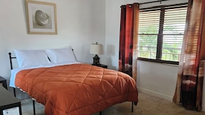 A bedroom with a bed, a ceiling fan, a window with curtains, and a wall-mounted lamp. - 213 Deluxe Single Room in a waterfront hotel in Singer Island, FL (Riviera Beach)