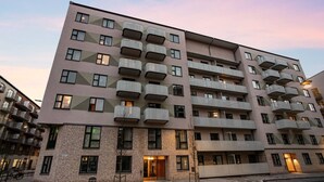 Kerrostalo, jossa on useita kerroksia, parvekkeet, tiiliverhous ja katutasossa sijaitseva sisäänkäynti.