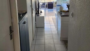 Um corredor estreito com uma área de cozinha de um lado e um espaço de estar com vista para o exterior do outro.