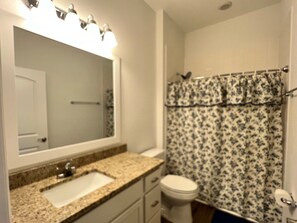 A bathroom with a sink, mirror, toilet, and shower curtain. - Wonderful 2-bedroom condo in exceptional retirement community near Orlando (Tavares)