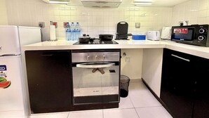 Una cocina compacta con horno empotrado, microondas y tostadora.